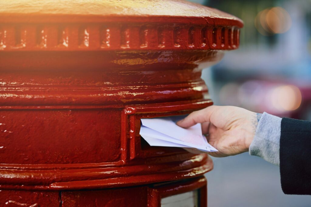 Cropped shot of a man posting mail into a postbox in the city